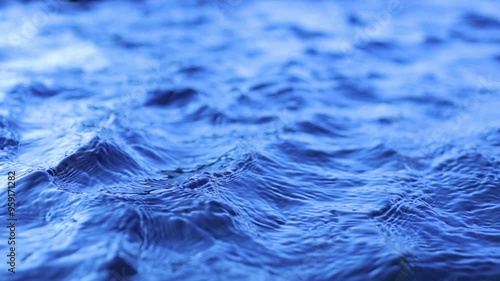 Natural background of blue water surface of sea or ocean with waves and light reflections. View of motion water swimming pool with ripples and sun glare. Unstable social issues.