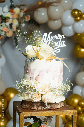 Un pastel de bodas de un nivel bellamente decorado con glaseado blanco y delicadas rosas blancas, ambientado en un lugar de bodas rústico pero elegante con una iluminación suave y romántica.