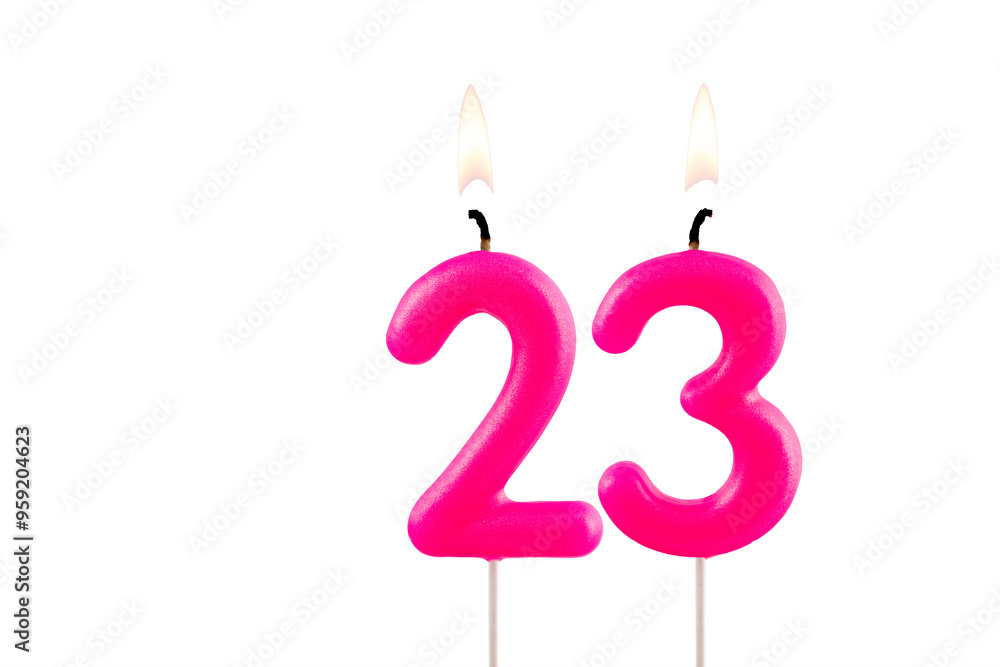 Pink number 23 birthday candle lit on white background Pink number 23 birthday candle lit on white background