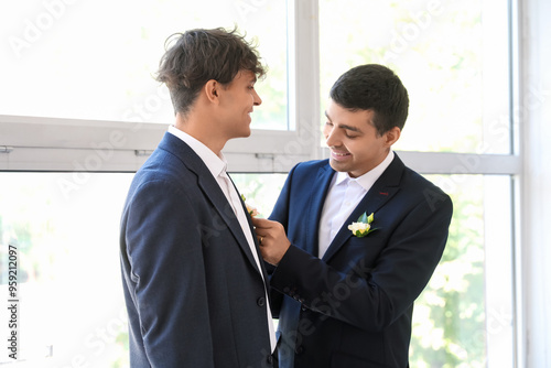 Young man fixing his husband's boutonniere on their wedding day