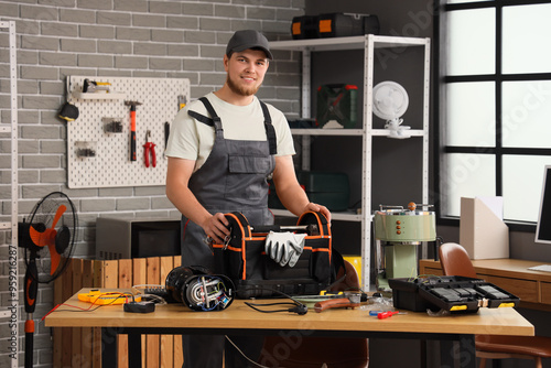 Male worker with bag of tools repairing coffee machine in workshop photo