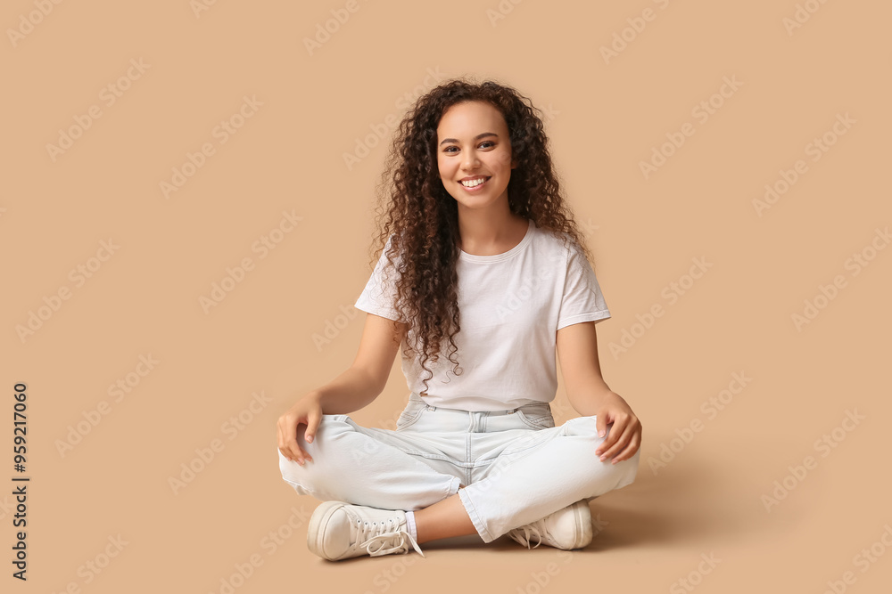 Happy young African-American woman sitting on beige background Happy young African-American woman sitting on beige background