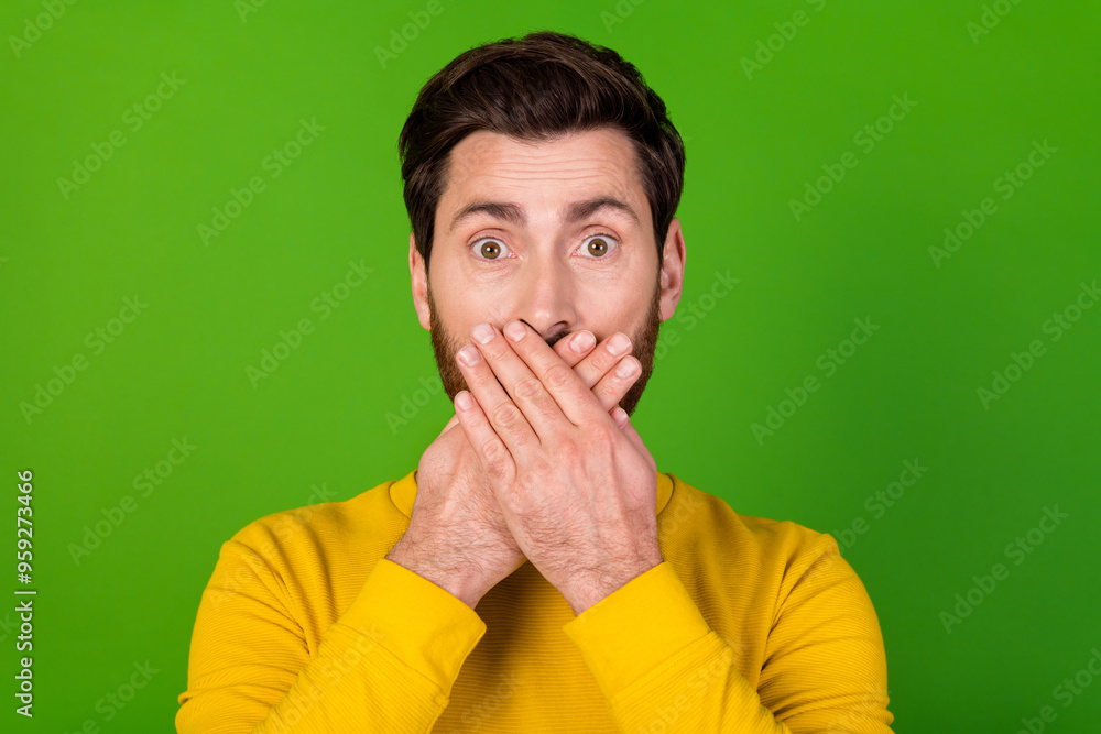 Photo of speechless man with stylish beard dressed yellow shirt palms cover mouth astonished staring isolated on green color background Photo of speechless man with stylish beard dressed yellow shirt palms cover mouth astonished staring isolated on green color background