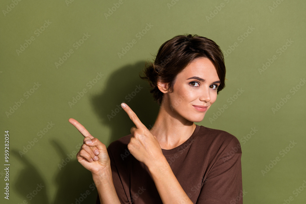 Obraz premium Portrait of satisfied woman with short hairstyle wear oversize t-shirt directing at logo empty space isolated on green color background
