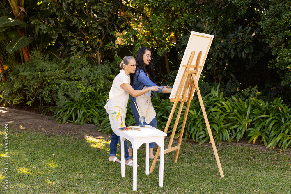 Fototapeta premium Painting on canvas, asian granddaughter and grandmother enjoying outdoor art activity together