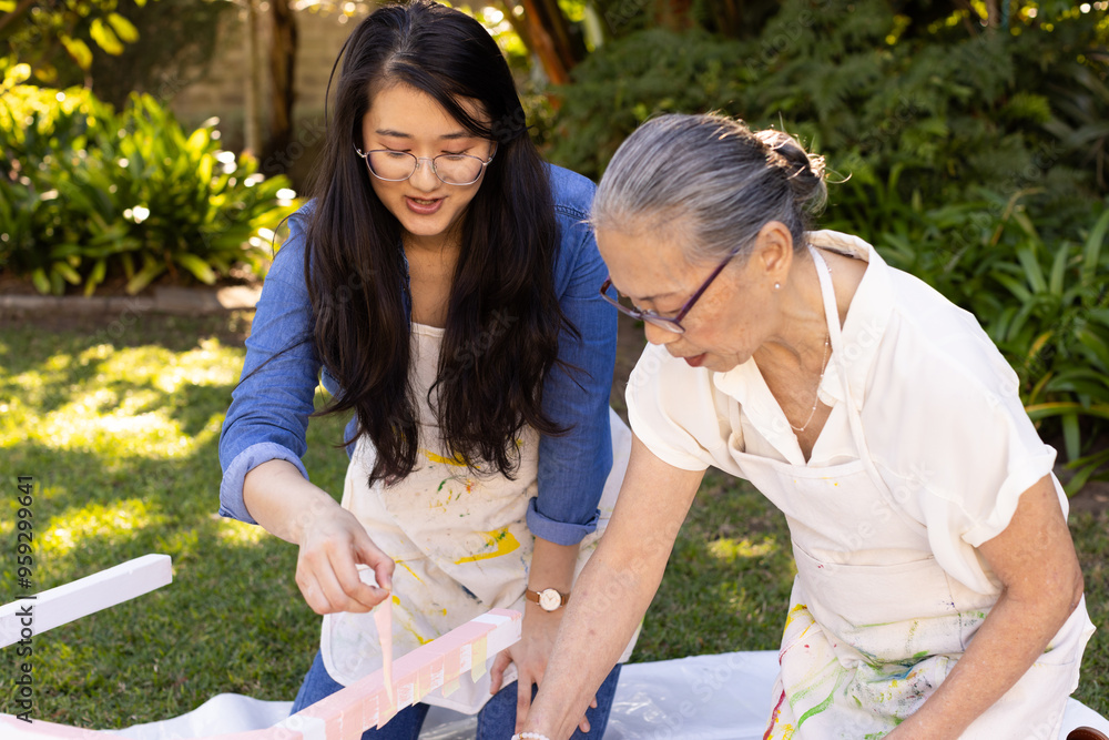 Fototapeta premium Painting together outdoors, asian granddaughter and grandmother enjoying creative activity