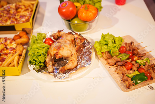 An indoor office party scene with no people around, featuring a desk filled with food pizza, bread, salad, chicken grill, French fries, and beerset against a night light with RGB lighting. photo