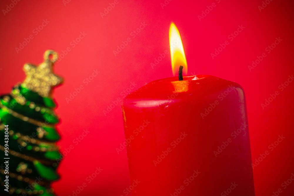 Red Candle and Christmas Tree Ornament against Red Background - Festive Holiday Decoration Red Candle and Christmas Tree Ornament against Red Background - Festive Holiday Decoration