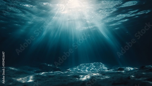 Sunlight beams through the deep blue ocean water, illuminating the sandy seafloor. photo