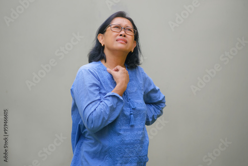 A woman is looking up, one hand on her neck, the other hand on her hip; frowning, thinking expression photo