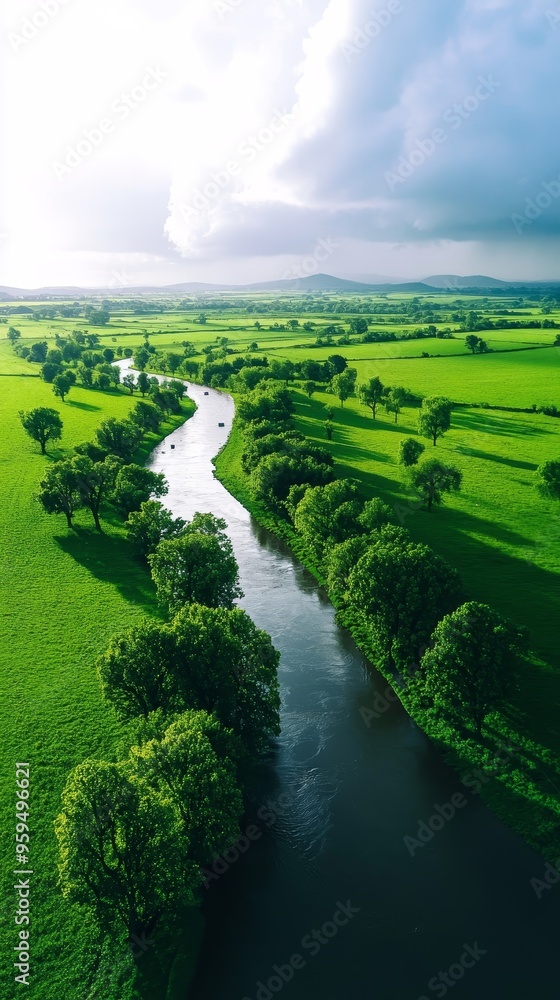 Fototapeta premium Aerial view of a serene river winding through lush greenery under a dramatic sky, showcasing the beauty of nature.