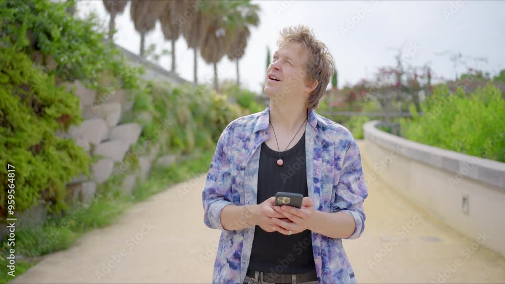 A young man is casually strolling outdoors, deeply engrossed in texting on his smartphone, surrounded by the vibrant greenery and beautiful natural landscape that nature generously offers to all A young man is casually strolling outdoors, deeply engrossed in texting on his smartphone, surrounded by the vibrant greenery and beautiful natural landscape that nature generously offers to all