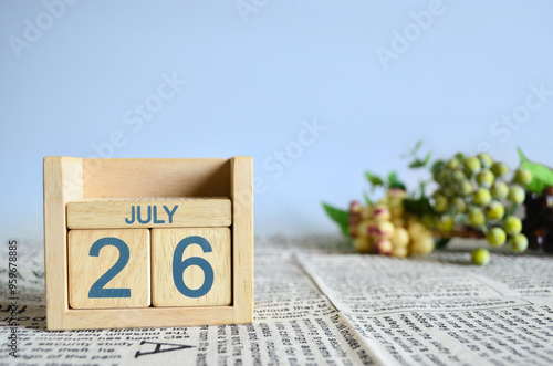 July 26, Calendar cover design with number cube with fruit on newspaper fabric and blue background.