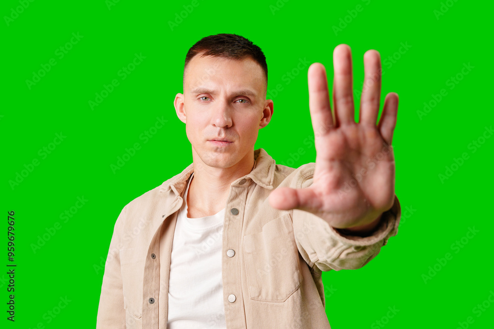 Man Holding Up Hand Against Bright Green Background While Displaying Serious Expression Man Holding Up Hand Against Bright Green Background While Displaying Serious Expression