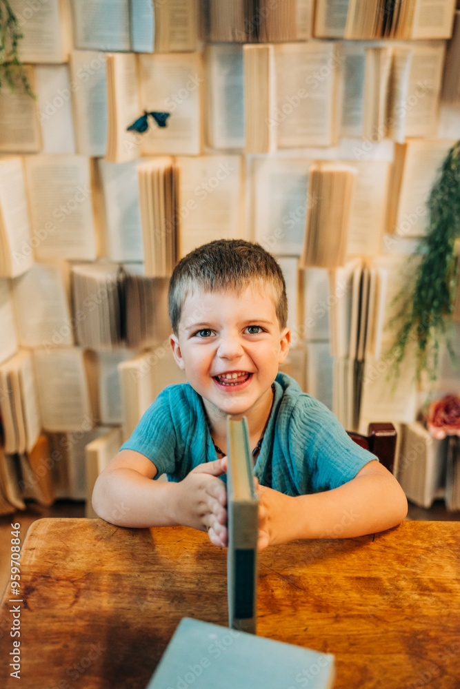 Smiling young boy sitting at a wooden desk with a book Smiling young boy sitting at a wooden desk with a book