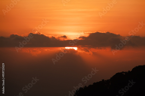 Sunset behind clouds and silhouetted hills