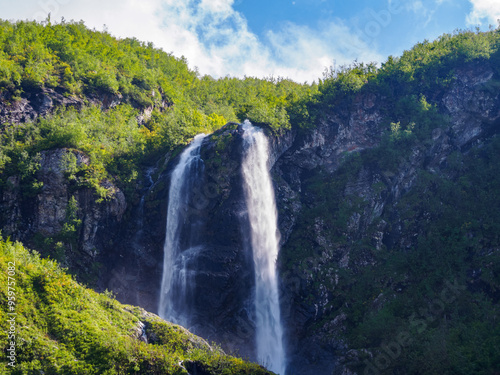 The waterfall against the backdrop of a majestic mountain fascinates with its beauty, creating an atmosphere of tranquility and the power of nature
