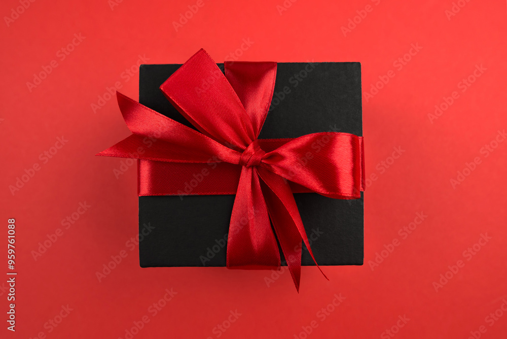 Top view photo of black gift box with red bow on isolated red background with empty space Top view photo of black gift box with red bow on isolated red background with empty space