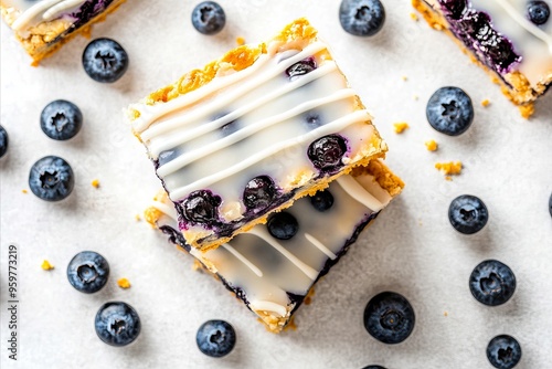 A close up of a stack of blueberry bars with white icing and blueberries