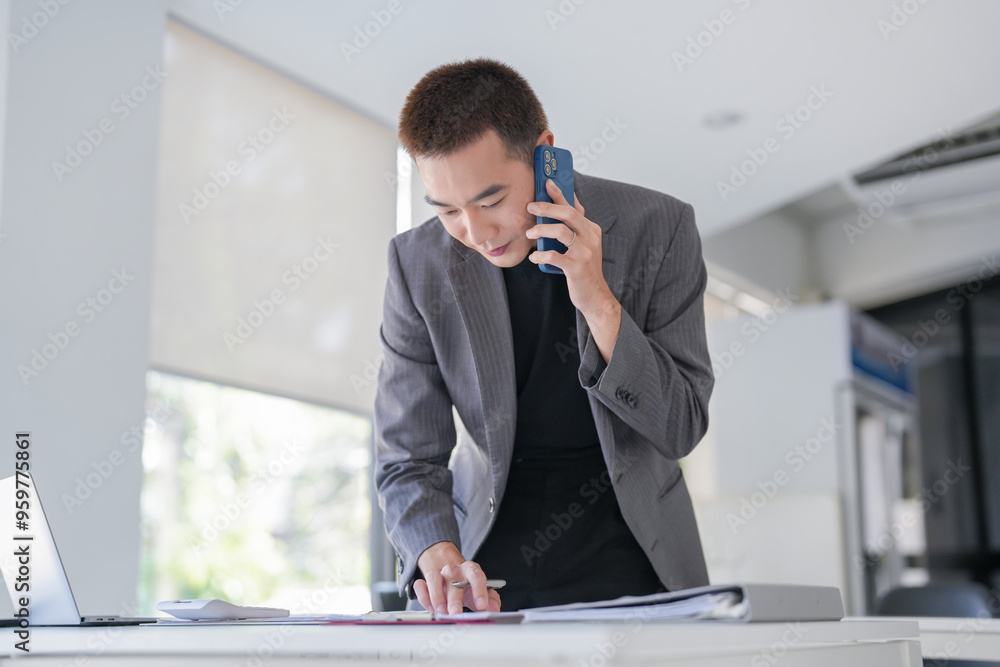 Handsome confident asian secretary man clever smart professional businessman talking on phone in office Handsome confident asian secretary man clever smart professional businessman talking on phone in office