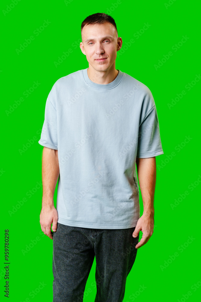 Young Man Standing Confidently Against Bright Green Background in Casual Attire Young Man Standing Confidently Against Bright Green Background in Casual Attire
