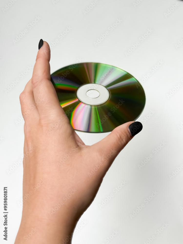 Hand holding a shiny compact disc against a minimalist white background Hand holding a shiny compact disc against a minimalist white background