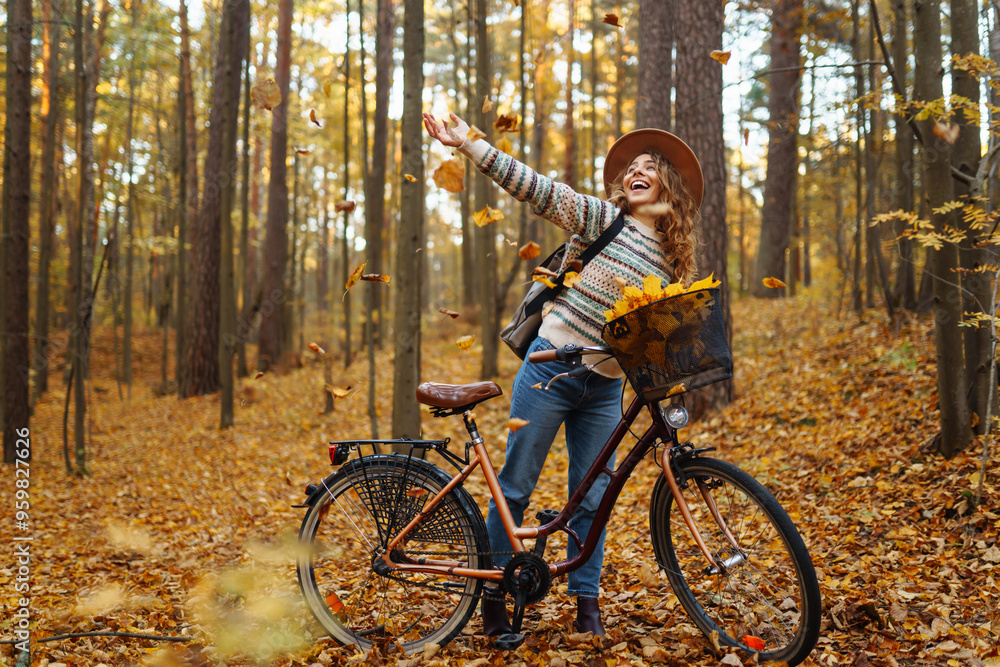 A woman biking through a golden autumn forest while enjoying a basket full of vibrant colorful leaves in the late afternoon sunlight. Active lifestyle. A woman biking through a golden autumn forest while enjoying a basket full of vibrant colorful leaves in the late afternoon sunlight. Active lifestyle.