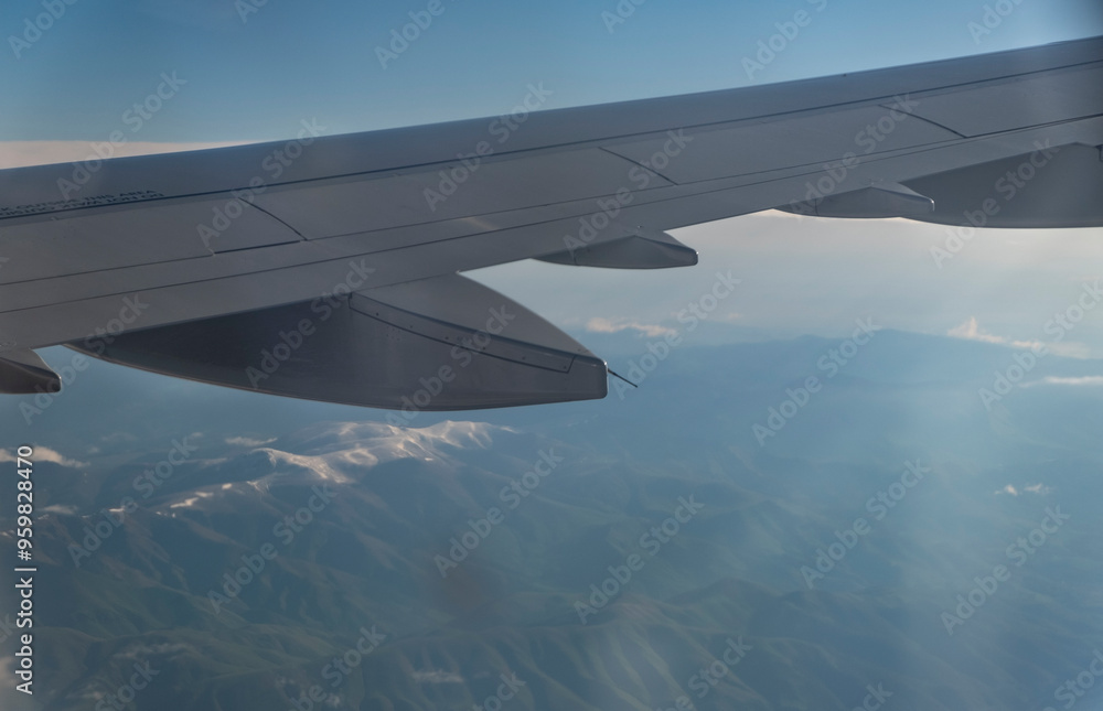 Obraz premium Wing of an airplane flying above the clouds in the blue sky.