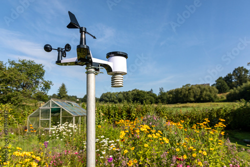 Private Wetterstation in einem Garten mit Gewächsahus und blühenden Sommerblumen