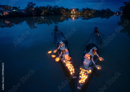 View of graceful vietnamese ladies in ao dai with glowing lanterns on a tranquil river at dusk, Hue, Vietnam. photo