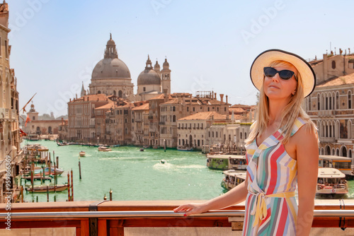 Stylish woman in a straw hat enjoying a sunny day in the charming city of Venice, strolling along the beautiful Grand Canal.