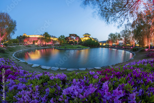 Suwon-si, Gyeonggi-do, South Korea - April 15, 2021: Night view of pink azalea and weeping willow against Northeast Bastion and Banghwasuryujeong Pavilion with a pond at Suwon Hwaseong Fortress photo