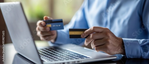 Wallpaper Mural A person holding credit cards while using a laptop, representing online shopping or banking activities in a modern digital environment. Torontodigital.ca