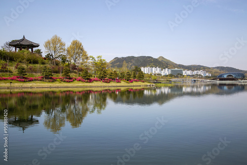 Sejong-si, South Korea - April 15, 2021: Spring view of an octagonal pavilion against high-rise apartments and Floating Stage Island with reflection on Sejong Lake