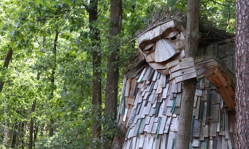 Canvas-taulu friendly wooden troll sculpture among green trees in forest, banner with copy space