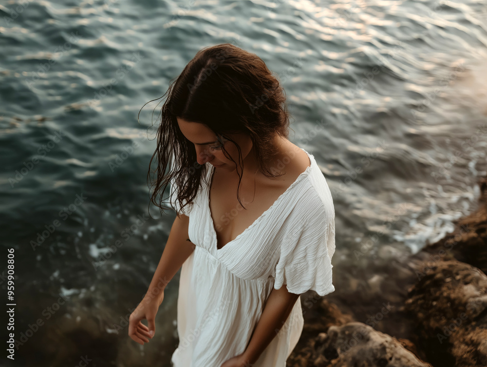 Fototapeta premium Serene Woman in White Flowy Dress Walking Peacefully by the Ocean Shore at Sunset, Capturing Nature’s Tranquility and Calmness