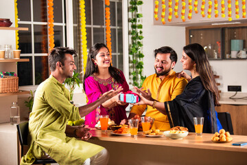 Happy Indian family and friends celebrating Diwali at home, sharing food and laughter