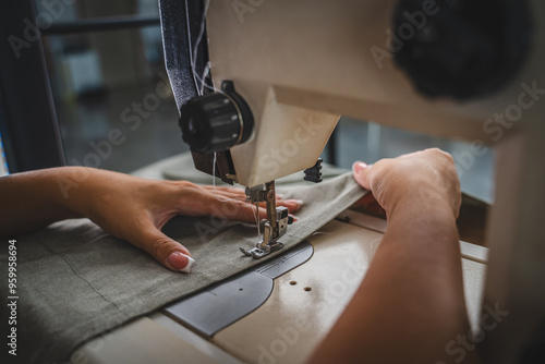 Close up on hands of unknown woman sewing on electric sewing machine
