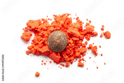 A piece of Betel Nut (Areca catechu) is placed over an orange-colored sindoor (vermilion) isolated on a white background. Top view. photo