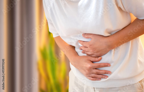 A woman clutching her abdomen for menstrual cramps pain in cycle period. Concept of health problems indigestion stomach upset unhealthy diet. Copy space for text	
 photo