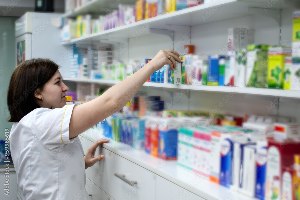 A girl pharmacist arranges medicines on the shelves of a pharmacy A girl pharmacist arranges medicines on the shelves of a pharmacy