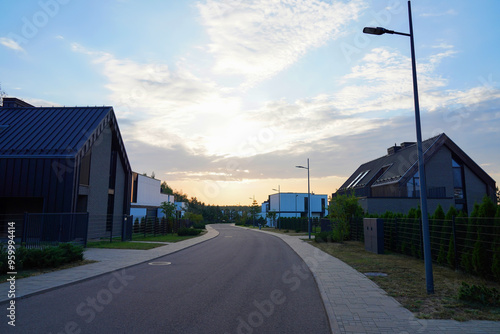 Barn House in village on sunset. Modern luxury house in suburb. Street with Wooden Scandi home. Modern Scandinavian Barnhouse Project. Contemporary barnhouse. Rows of Barn Houses along road village.