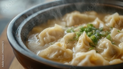 Close-up of a steaming bowl of wonton soup.