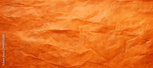 Vibrant textured orange paper with visible creases under soft lighting in a creative workspace