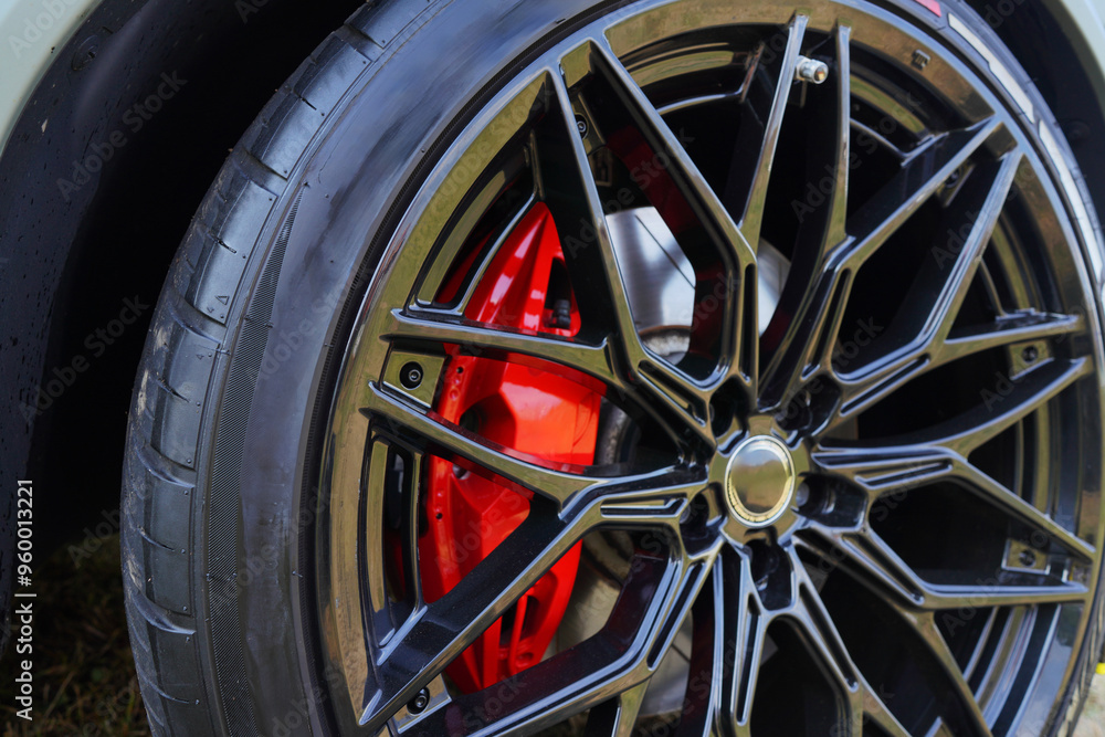 Fototapeta premium Alloy wheel with calipers and racing brakes of the sport car. Racing brake disc and low profile tyres. Race car test driving. Lower-profile tires of drag and drift cars. High-performance sports cars.
