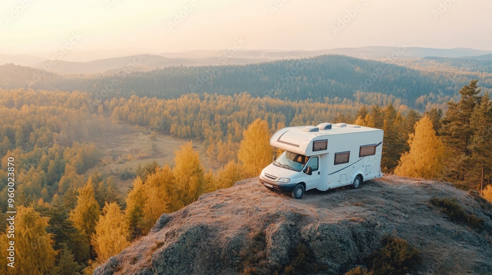 White RV on a top of autumn mountain, early morning light, distant yellow forest White RV on a top of autumn mountain, early morning light, distant yellow forest