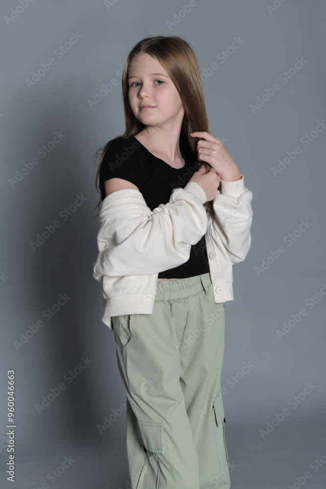 A young girl in a black top and green pants stands with her hands together, looking away with a pensive expression. This image highlights the contemplative nature of children, capturing a serene and A young girl in a black top and green pants stands with her hands together, looking away with a pensive expression. This image highlights the contemplative nature of children, capturing a serene and