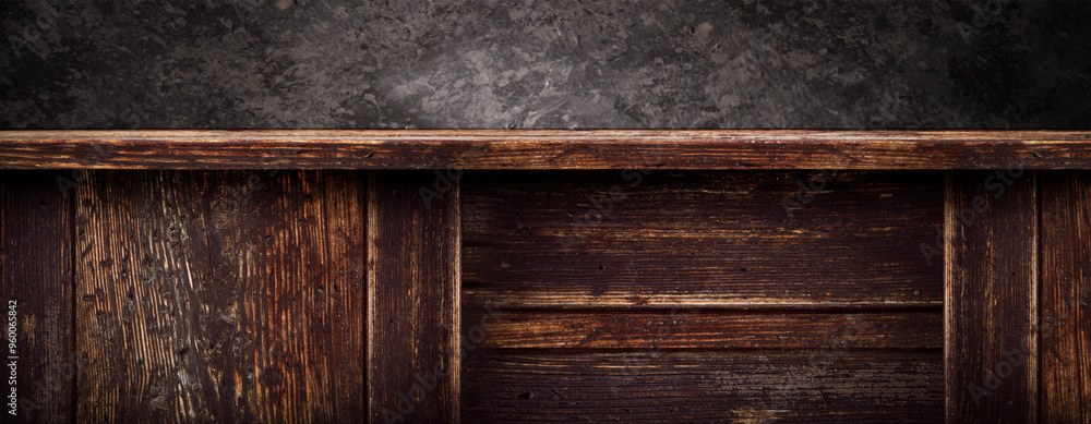 Empty dark rustic wooden counter in front of a black stone wall. Background for product display with space for text. Empty dark rustic wooden counter in front of a black stone wall. Background for product display with space for text.