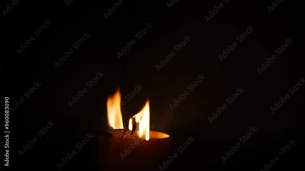 A burning candle with the flame moving. Fire in a dark space A burning candle with the flame moving. Fire in a dark space