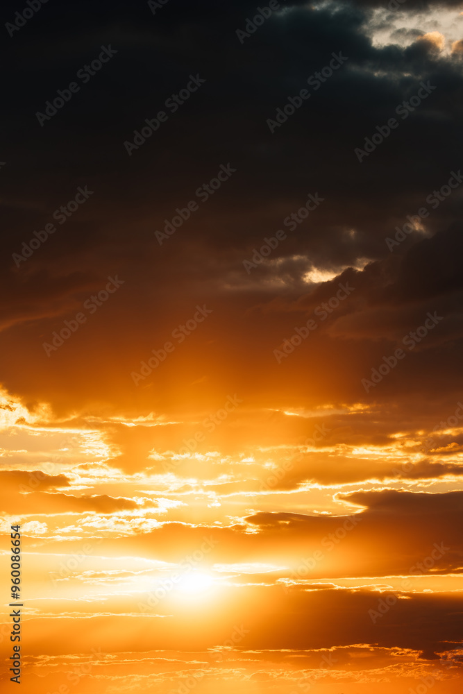 Fototapeta premium Natural Bright Dramatic Sky In Sunset Dawn Sunrise. Amazing Bold Golden Sunset Sunrise Sky Background. Warm Yellow And Orange Colors. Dark Clouds with Sun